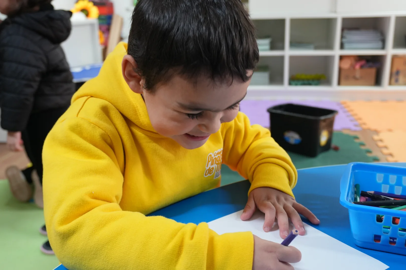 Menino desenhando na mesa azul