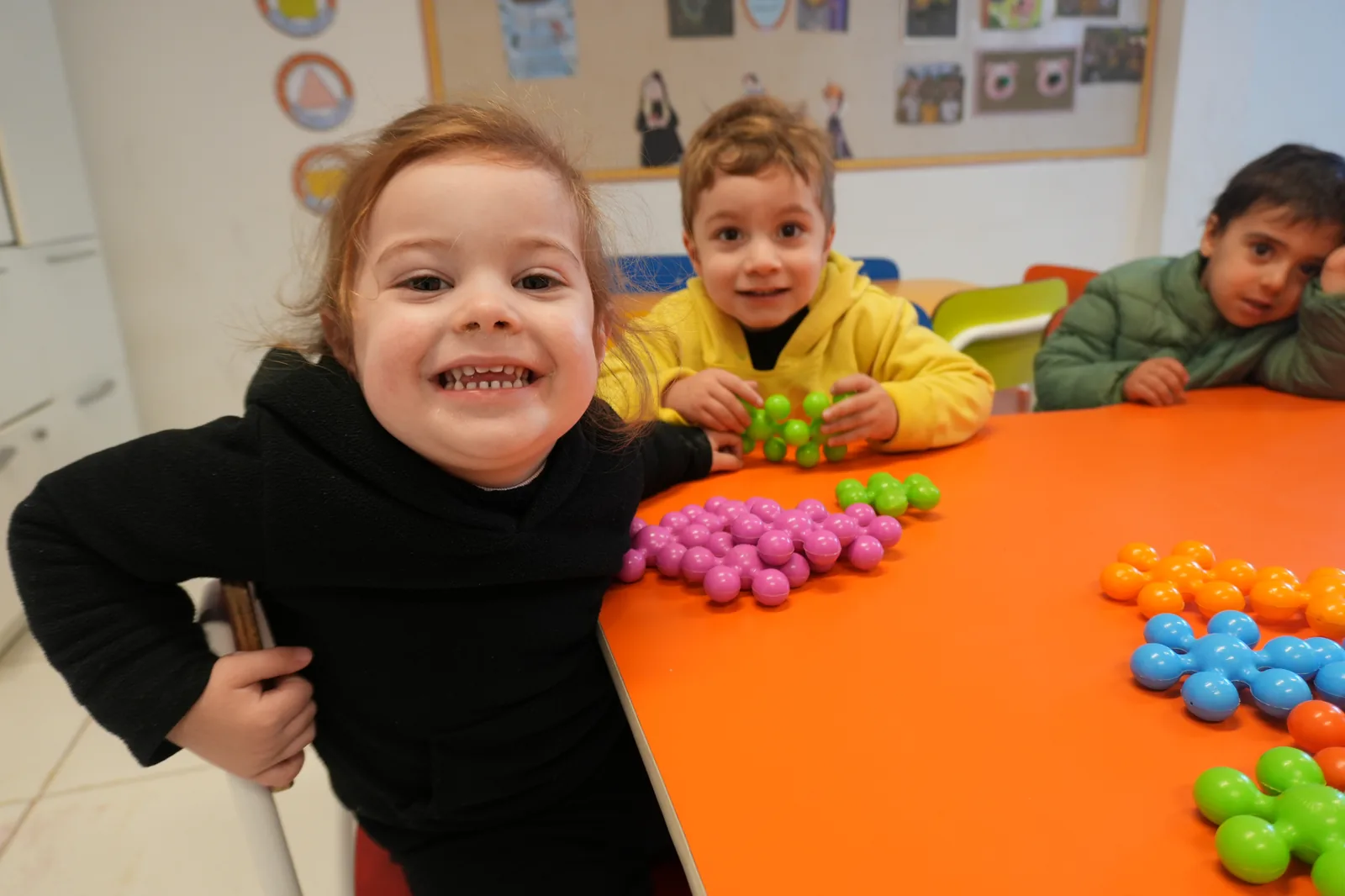 Crianças brincando com blocos na mesa laranja